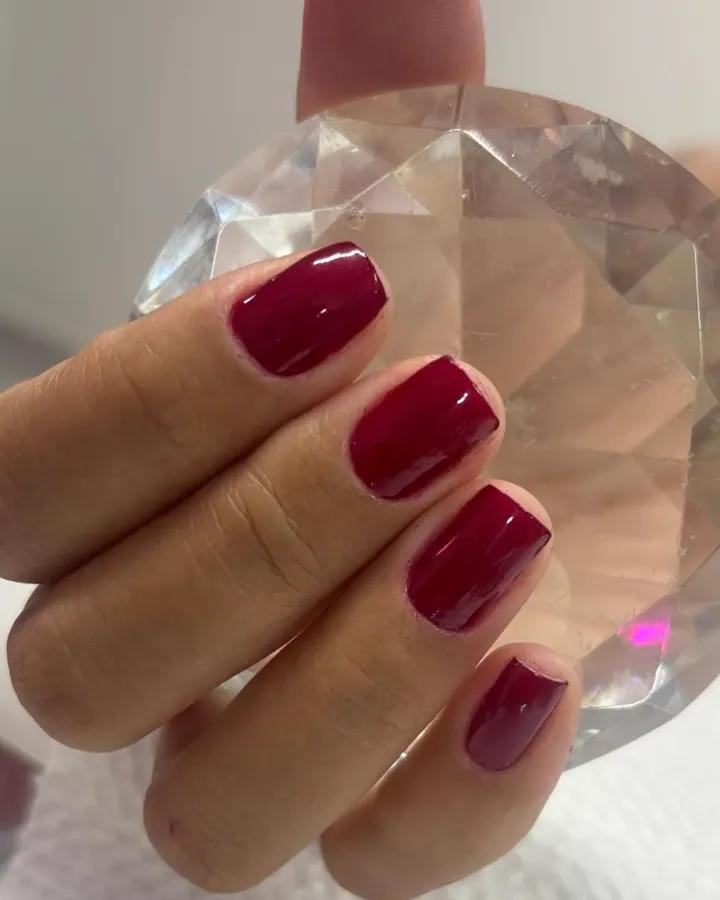 Unhas vermelho escuro sobre cristal